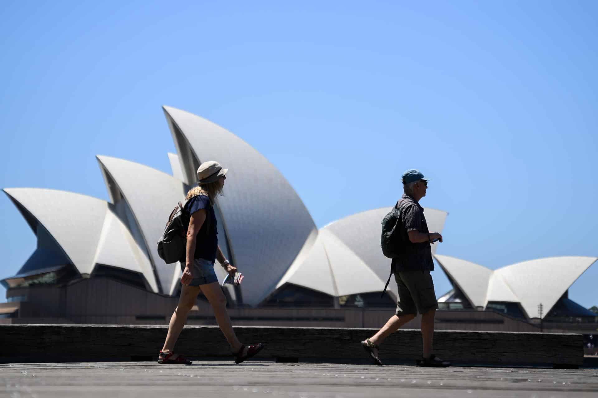 Dos personas pasan este martes delante de la Casa de la Ópera en Sídney en medio de una ola de claro. EFE/EPA/BIANCA DE MARCHI AUSTRALIA AND NEW ZEALAND OUT