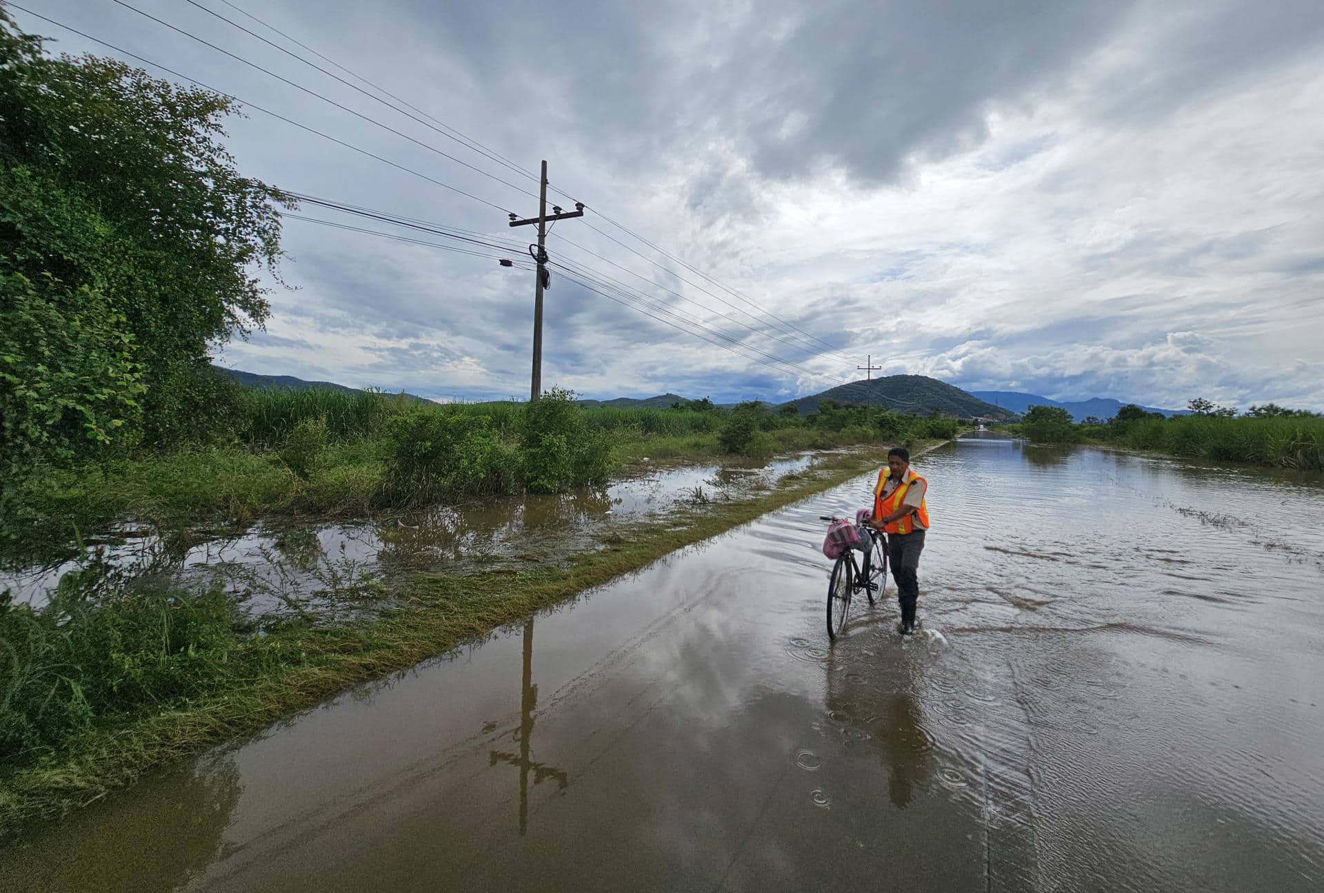 Una persona cruza con su bicicleta por una calle inundada. EFE/José Valle