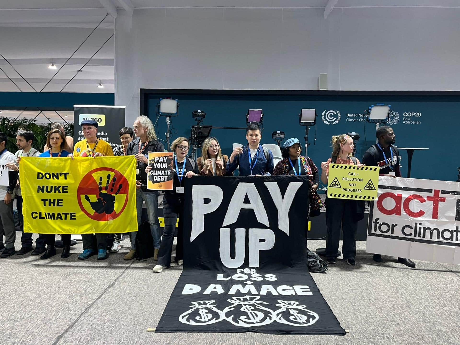 Cerca de un centenar de activistas se manifestaron hoy de manera casi silenciosa en la COP29 de Bakú, donde formaron una cadena en torno a salas de plenarios con pancartas y tararearon canciones de protesta, para denunciar que la organización de la cumbre les había prohibido hablar, cantar o dar palmas.EFE/Marta Montojo