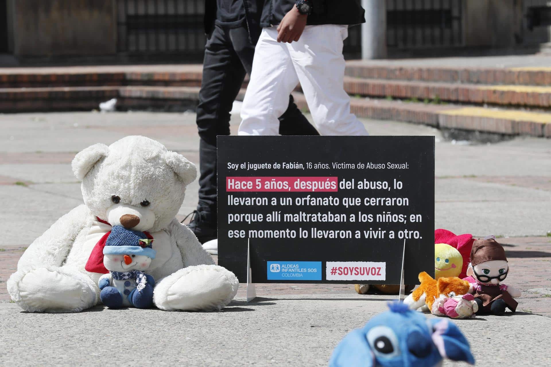 Fotografía de archivo de varios juguetes junto a un cartel de protesta que resume una historia de abuso a un niño, durante un plantón en la Plaza del céntrico barrio 20 de Julio, en Bogotá (Colombia). EFE/ Carlos Ortega