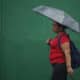 Fotografía de archivo en donde una mujer se protege de la lluvia en el centro de San Salvador (El Salvador). EFE/Rodrigo Sura