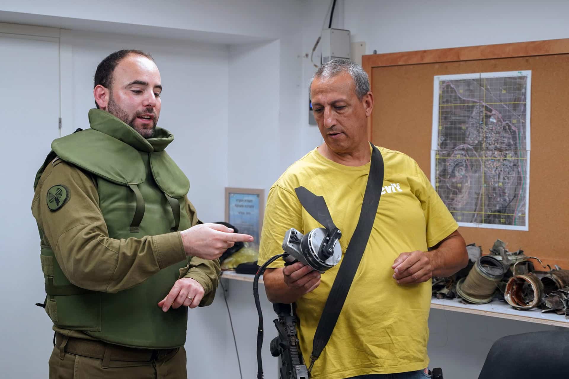 El Teniente Coronel Nadau Shoshani, portavoz internacional de las Fuerzas de Defensa de Israel (i) y David Azulai (d), muestran restos de proyectiles y drones lanzados por la milicia chií Hizbulá.- EFE/ Alejandro Ernesto