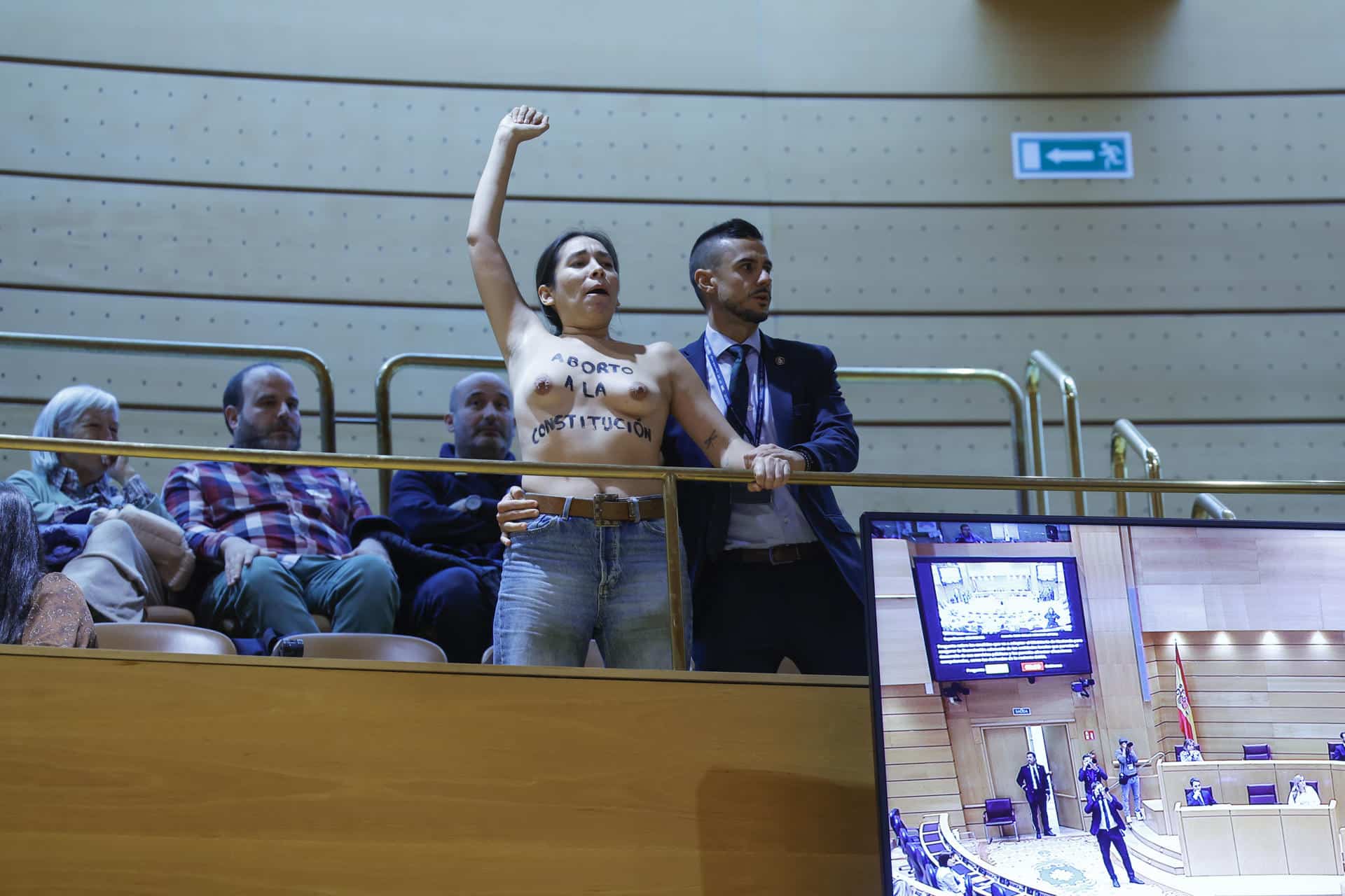 Una de las dos mujeres activistas de Femen con el torso desnudo y mensajes en favor del aborto escritos en su piel, que han interrumpido con gritos el pleno del Senado durante la sesión de control al Gobierno de este martes, antes de ser desalojadas de la tribuna de invitados. EFE/ Zipi