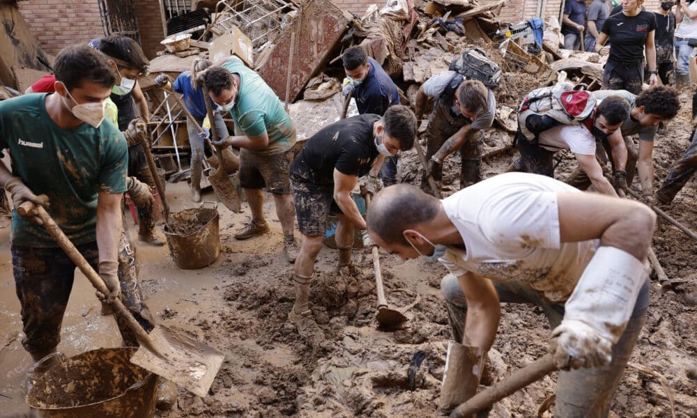 Varias personas retiran el lodo acumulado en una calle de la localidad valenciana de Paiporta, este sábado. Por tercer día consecutivo una marea de voluntarios ha llegado este sábado a barrios del sur de la ciudad de València y a los pueblos de la comarca vecina de l’Horta Sud asolados por la dana para luchar contra un fango, donde grupos especializados de los equipos de intervención buscan cadáveres en garajes o fosos aún anegados.EFE/ Biel Alino