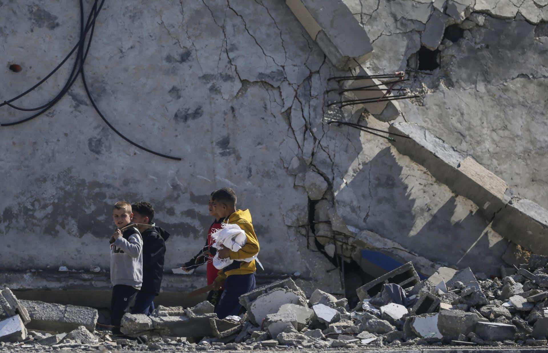 En la imagen de archivo, niños palestinos caminan junto a su casa destruida tras un ataque aéreo israelí contra el campo de refugiados de Al Maghazi, en el sur de la Franja de Gaza. EFE/EPA/MOHAMMED SABLE