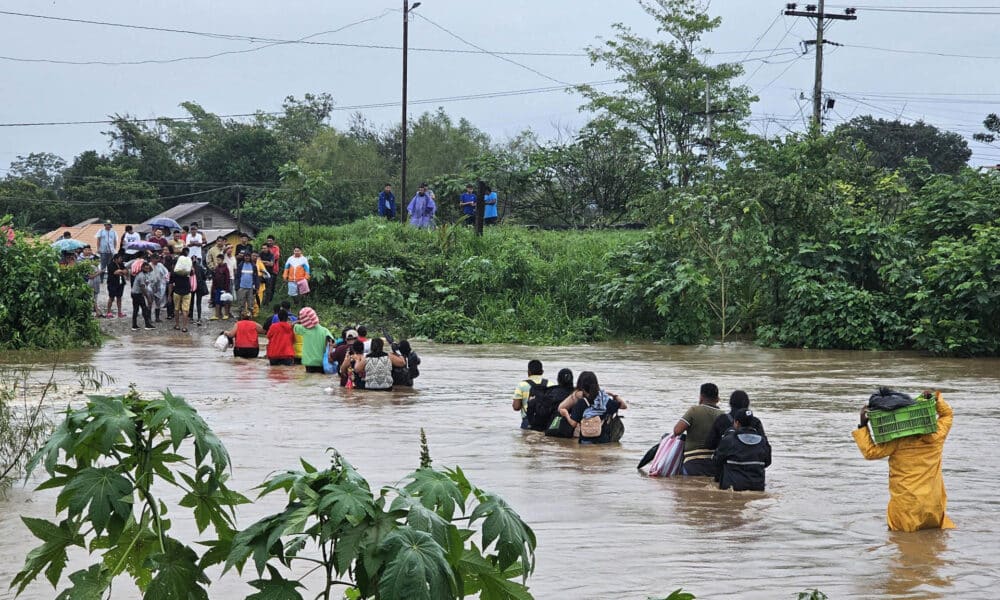 Habitantes de Campo Amapa, ubicado en la zona bananera de El Progreso, cruzan con sus pertenencias por un río en medio de las inundaciones causadas por la tormenta tropical Sara este sábado, en El Progreso (Honduras). EFE/ José Valle