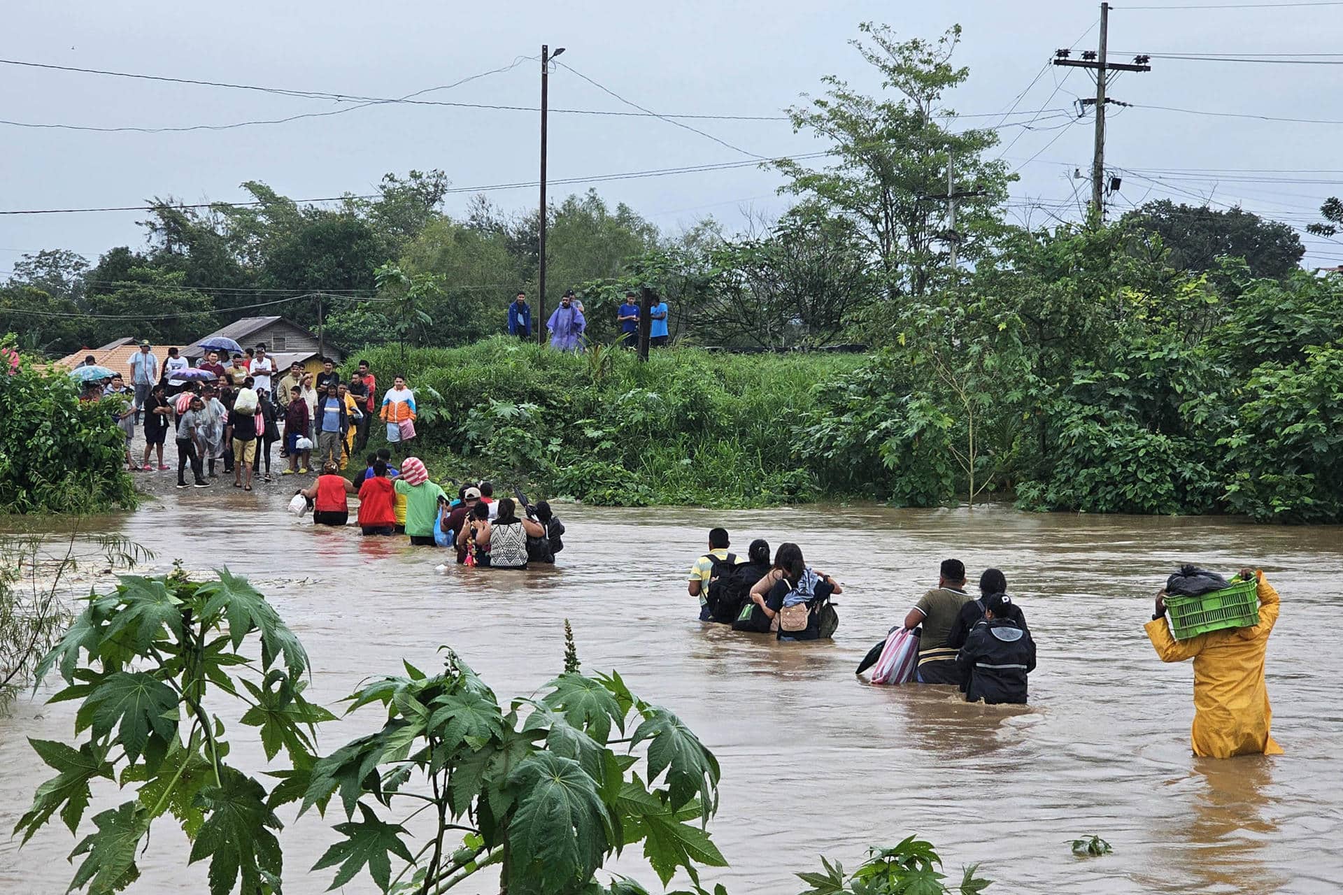 Habitantes de Campo Amapa, ubicado en la zona bananera de El Progreso, cruzan con sus pertenencias por un río en medio de las inundaciones causadas por la tormenta tropical Sara este sábado, en El Progreso (Honduras). EFE/ José Valle