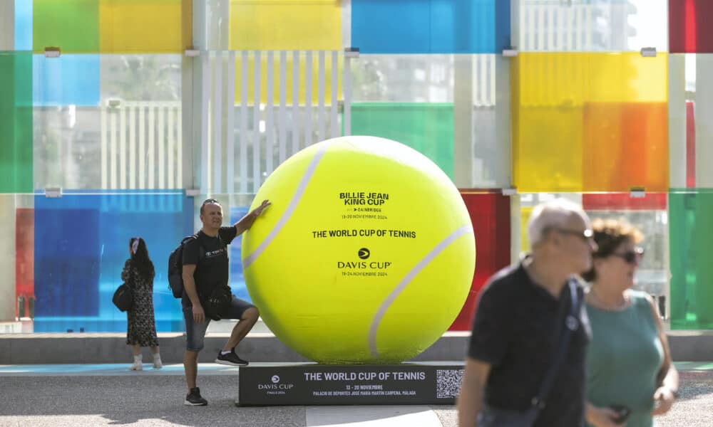 -Una persona se fotografía junto a una de la pelotas de tenis gigantes que se han instalado por el centro de la ciudad dentro de los preparativos para la celebración de las finales de la Copa Billie Jean King, en una foto de archivo. EFE/Daniel Pérez