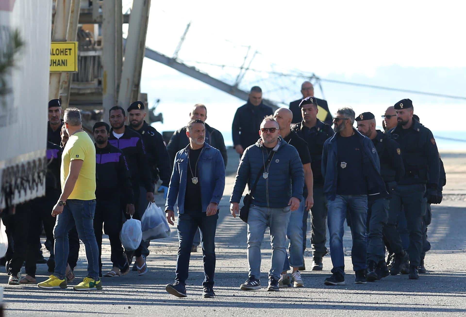 Un grupo de migrantes (L) interceptados en aguas internacionales alrededor de Italia, desembarcan en el buque de la Armada Italiana Libra en Shengjin, Albania, el 08 de noviembre de 2024. Italia ha enviado un grupo de 8 migrantes a Albania, después de que un grupo anterior fuera rechazado en octubre por no pasar el proceso de verificación, en un plan destinado a disuadir los peligrosos cruces marítimos al procesar las solicitudes de asilo fuera de la UE. La iniciativa enfrentó reveses legales después de que los tribunales italianos dictaminaran que los migrantes no podían ser retenidos en Albania debido a preocupaciones sobre su estatus legal. En respuesta, el gobierno italiano ajustó el marco legal, esperando que esto fortaleciera la política, que permite alojar temporalmente a hasta 3,000 hombres no vulnerables en instalaciones gestionadas por Italia en Albania. (Italia) EFE/EPA/MALTON DIBRA