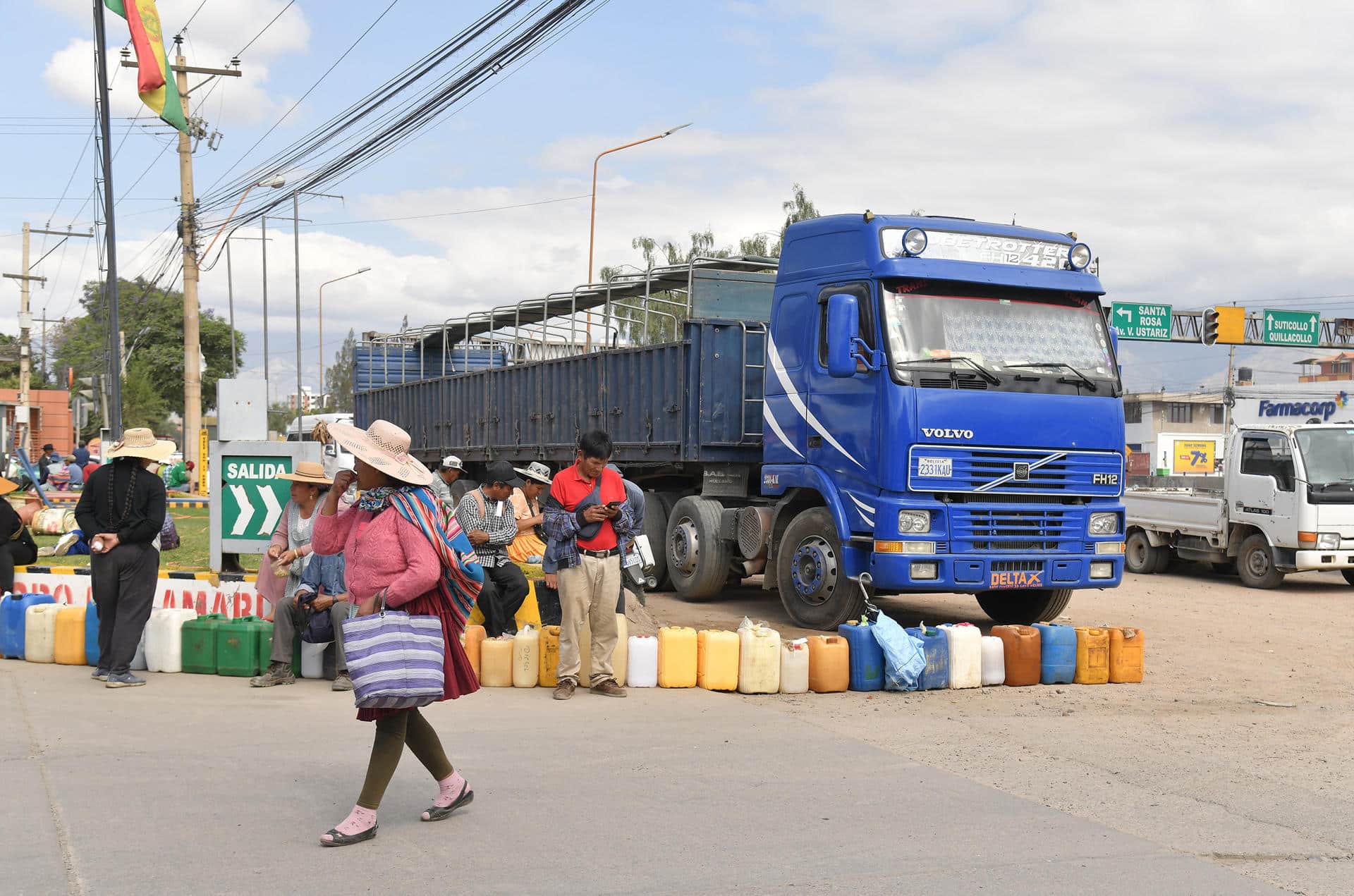 Una mujer Quechua camina delante de personas que hacen filas para comprar combustible en una estación de servicio este jueves en Cochabamba (Bolivia). EFE/Jorge Abrego