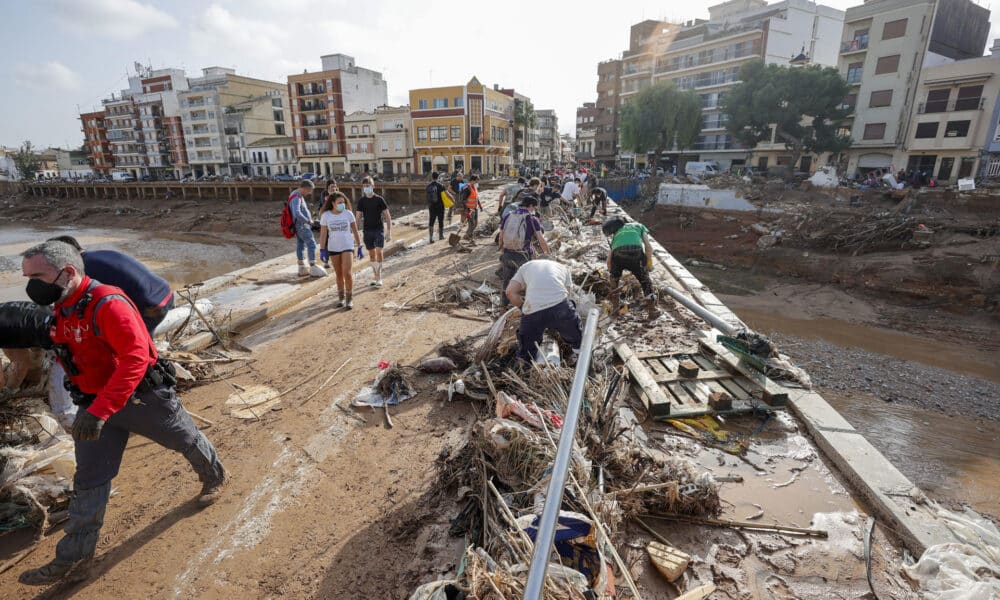 Decenas de voluntarios trabajan para despejar uno de los puentes de Paiporta, Valencia, este lunes. EFE/ Manuel Bruque