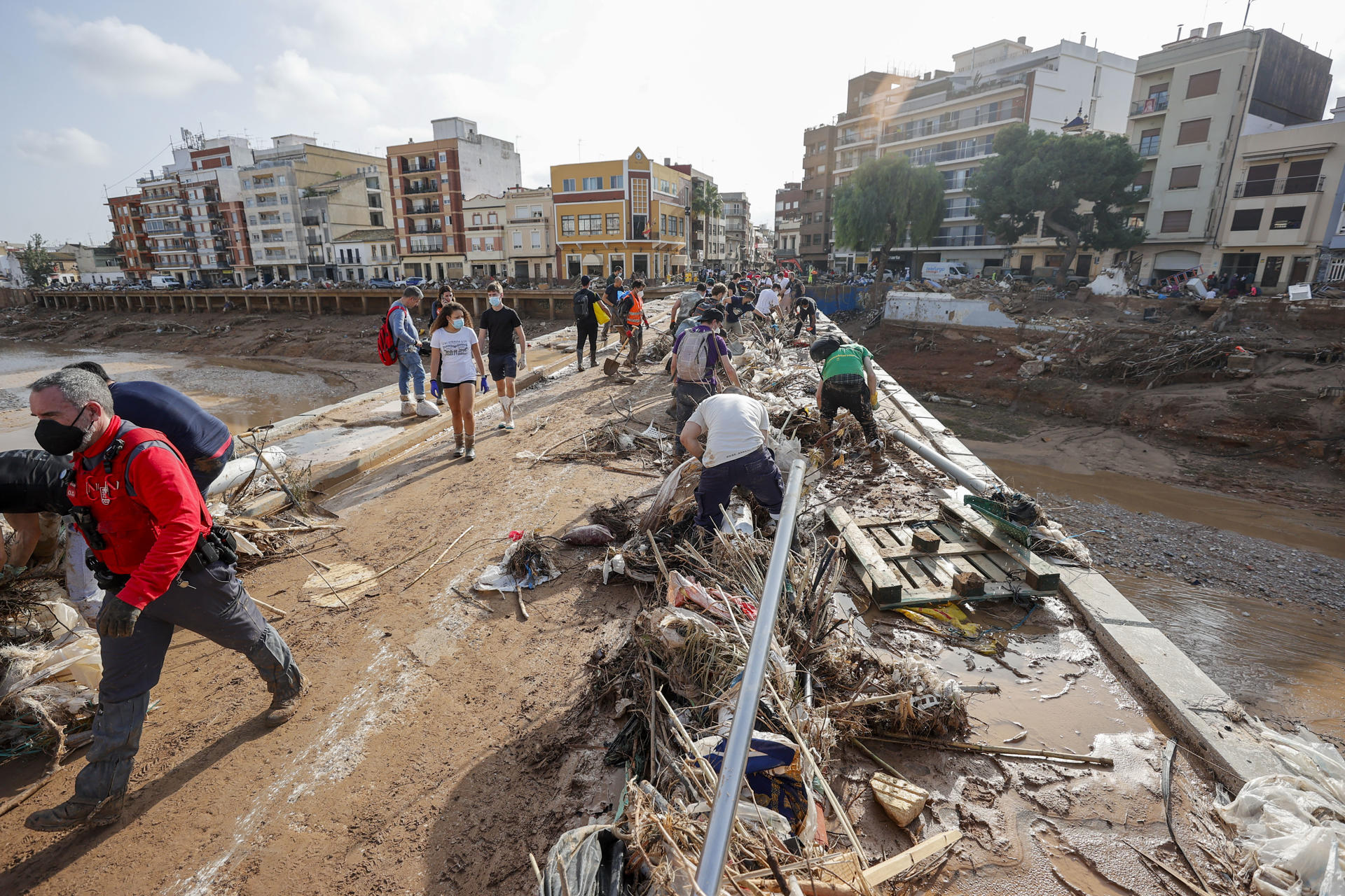 Decenas de voluntarios trabajan para despejar uno de los puentes de Paiporta, Valencia, este lunes. EFE/ Manuel Bruque