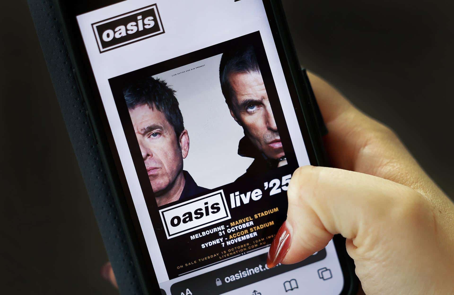 Una persona observa el póster promocional de la gira mundial de la banda británica Oasis. EFE/ANDY RAIN