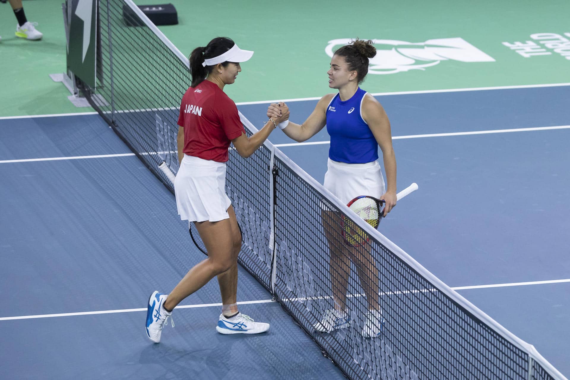 La tenista de japonesa Moyuka Uchijima (i) saluda a la italiana Jasmine Paolini tras su partido perteneciente a los cuartos de final de la Billie Jean King Cup, disputado este sábado en Málaga. EFE/Carlos Díaz.