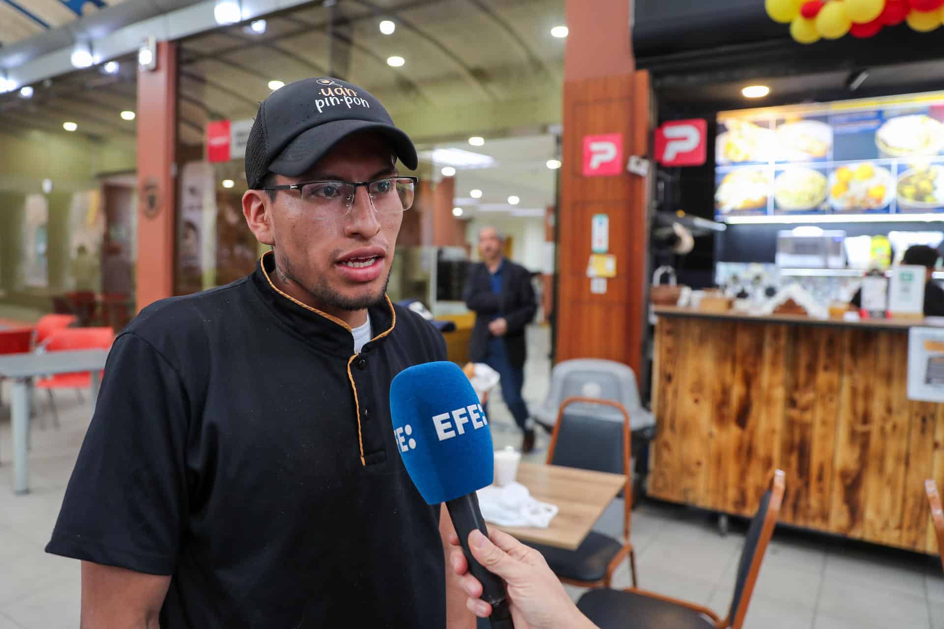 El empleado de una cafetería habla con EFE en el centro histórico de Cuenca (Ecuador), sede de la XXIX Cumbre Iberoamericana de Jefas y Jefes de Estado y de Gobierno, en la que el empleo será un tema preponderante. EFE/José Jácome