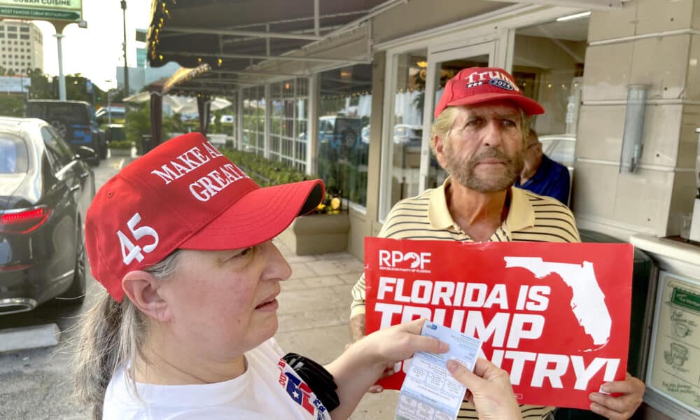 Ania Fresquet (i), una votante inscrita en la lista demócrata pero que vota por Donald Trump, muestra su tarjeta de votación junto a Miguel Saavedra, de la 'Vigilia Mambisa', el lunes 4 de noviembre de 2024 en frente del icónico restaurante Versailles de la Pequeña Habana en Miami, Florida (EE.UU.). EFE/Ana Milena Varón