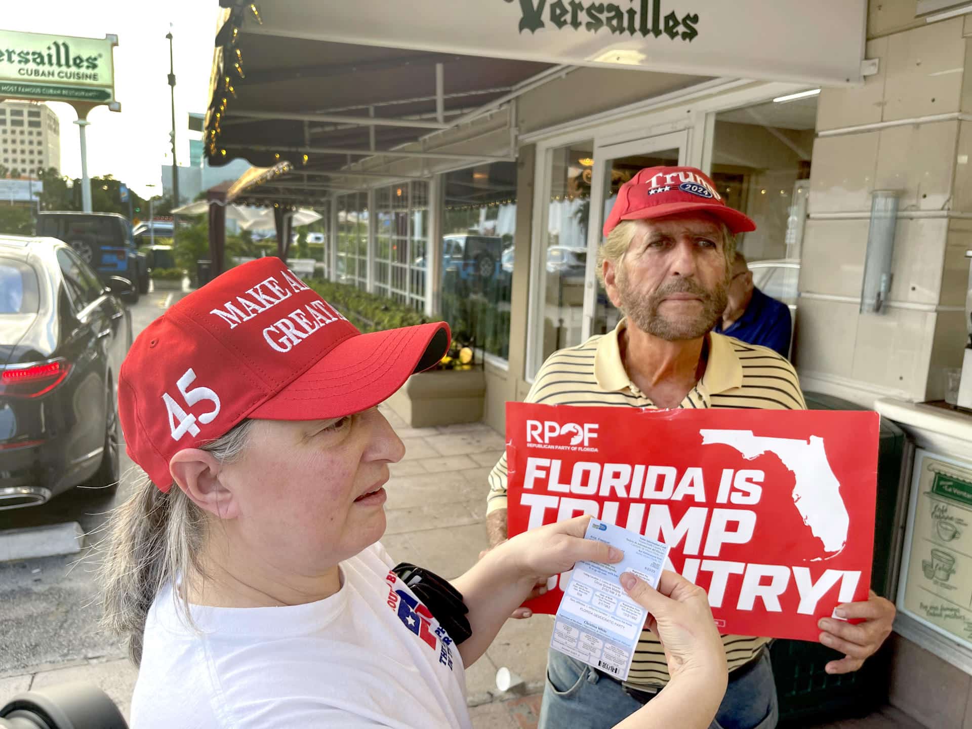 Ania Fresquet (i), una votante inscrita en la lista demócrata pero que vota por Donald Trump, muestra su tarjeta de votación junto a Miguel Saavedra, de la 'Vigilia Mambisa', el lunes 4 de noviembre de 2024 en frente del icónico restaurante Versailles de la Pequeña Habana en Miami, Florida (EE.UU.). EFE/Ana Milena Varón