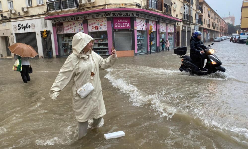 Una mujer hace fotos en Málaga durante las inundaciones sucedidas en el sur de España. EFE/María Alonso