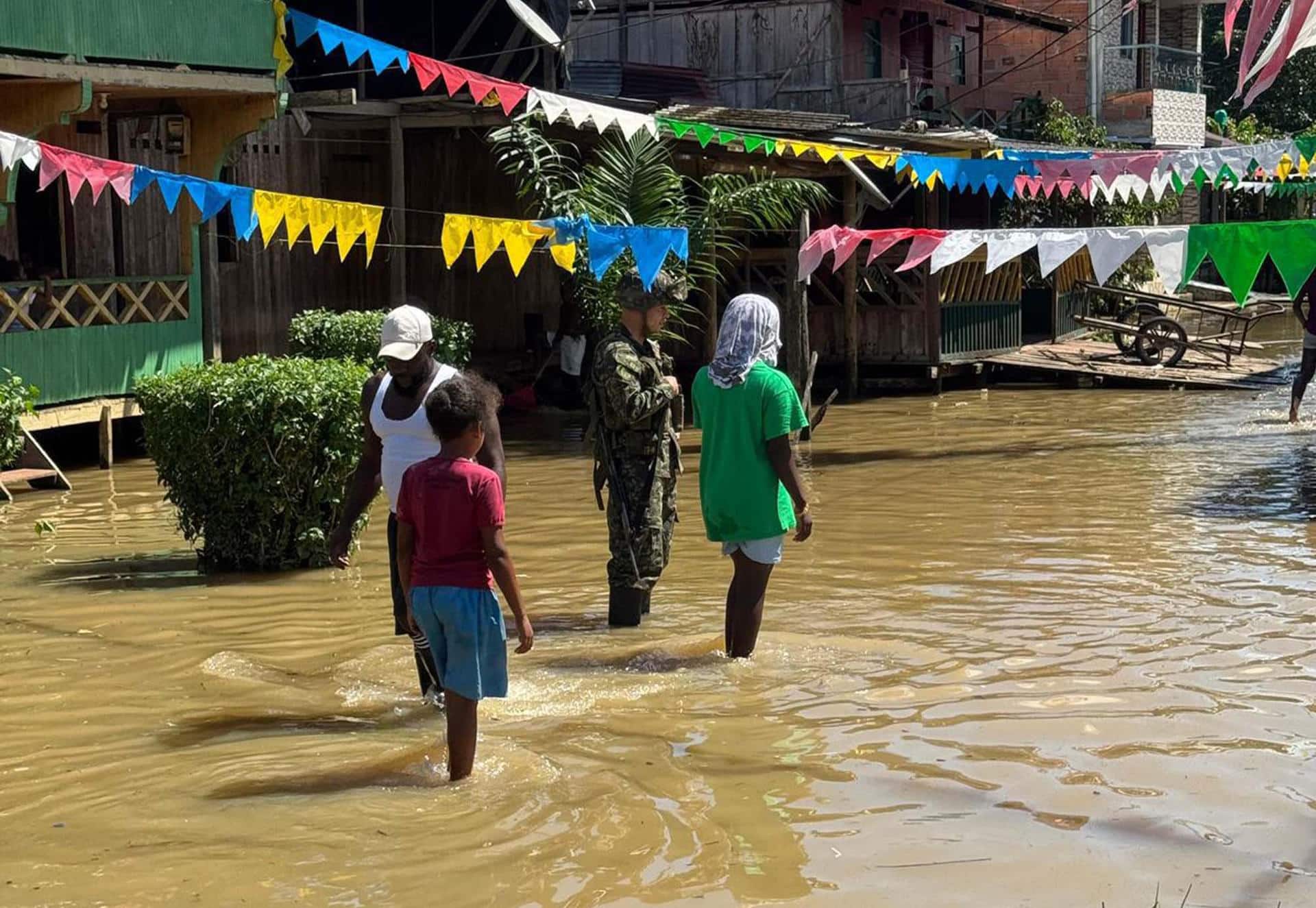 Fotografía cedida por el Ejército de Colombia que muestra un soldado con tres personas en una calle inundada en Alto Baudó (Colombia). EFE/Ejército de Colombia