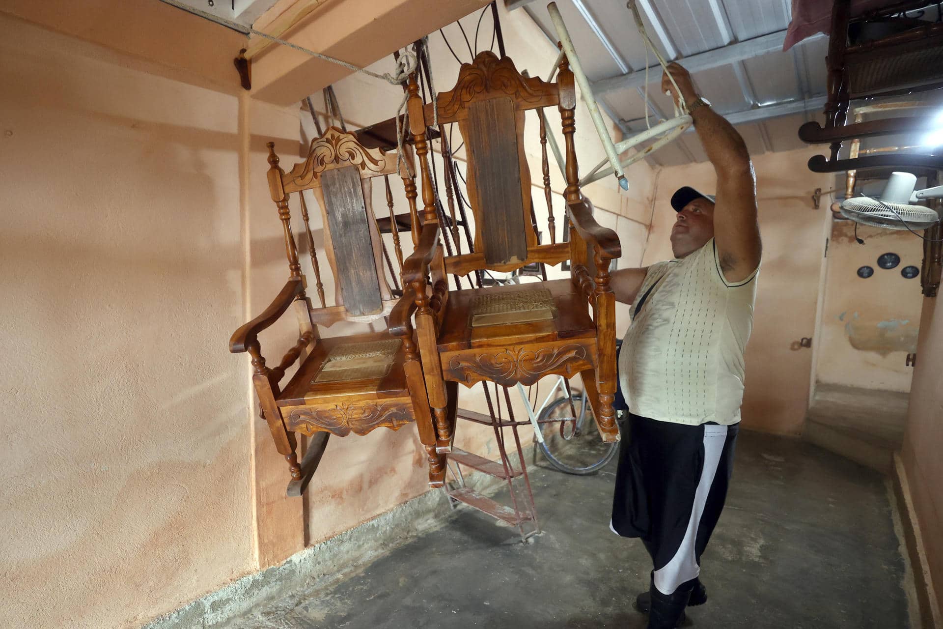 Un hombre cuelga unas sillas al techo de su vivienda ante la llegada del huracán Rafael, este miércoles en Surgidero de Batabanó, un puerto pesquero en la provincia occidental de Mayabeque, a unos 50 kilómetros al sur de La Habana (Cuba). EFE/ Ernesto Mastrascusa