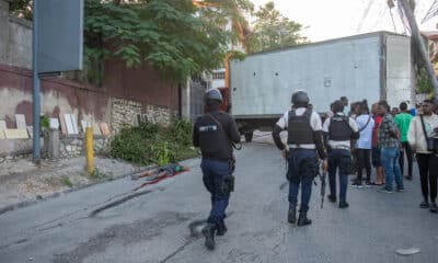 Fotografía de archivo de integrantes de la Policía de Haití pasando frente a los restos de un pandillero incinerado este martes, en una calle de Puerto Príncipe (Haití). EFE/ Johnson Sabin