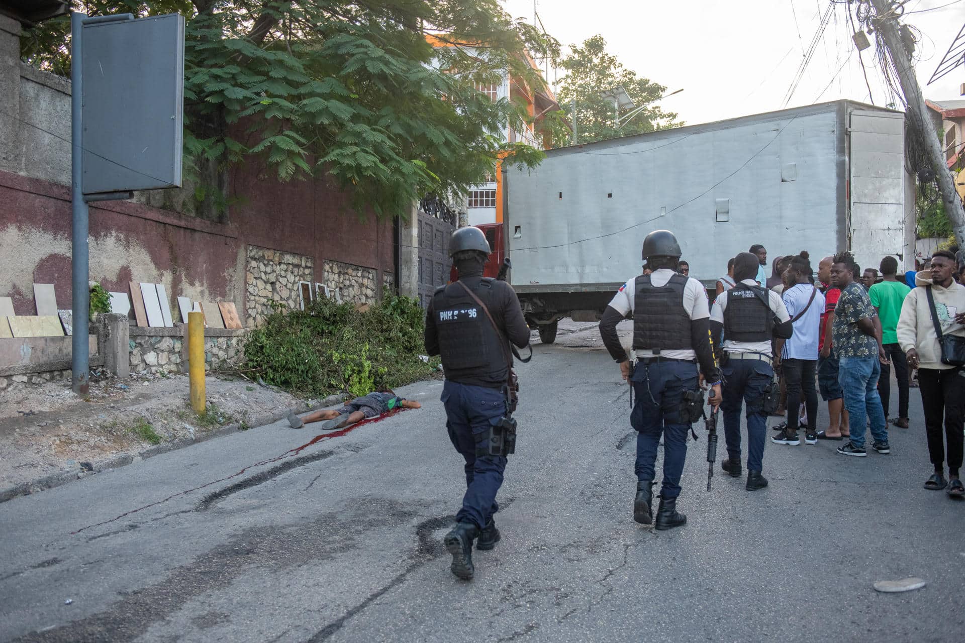 Fotografía de archivo de integrantes de la Policía de Haití pasando frente a los restos de un pandillero incinerado este martes, en una calle de Puerto Príncipe (Haití). EFE/ Johnson Sabin