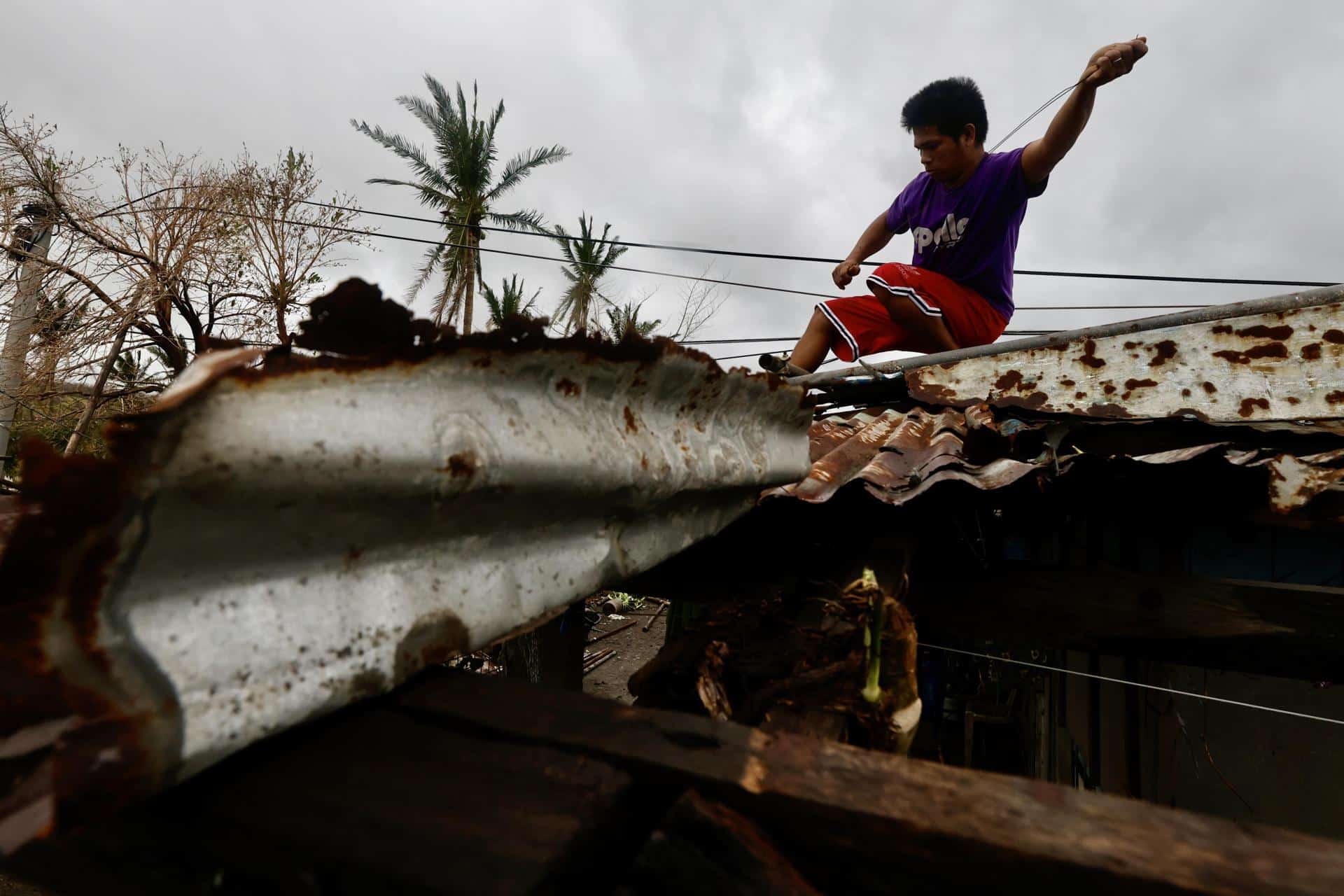 Santa Ana (Philippines), 14/11/2024.- A villager reinforces the roof of a damaged house caused by a recent typhoon in the coastal municipality of Santa Ana, Cagayan province, Philippines, 14 November 2024. After the onslaught of Typhoons Toraji, Trami, Yinxing and Kong-rey, the Philippines now brace for the landfall of Typhoon Usagi, the fifth major storm to hit the country in three weeks. Government officials warned residents of possible landslides due to ground saturation from successive typhoons impacting the Luzon island. (tormenta, deslizamiento de tierras, Filipinas) EFE/EPA/FRANCIS R. MALASIG