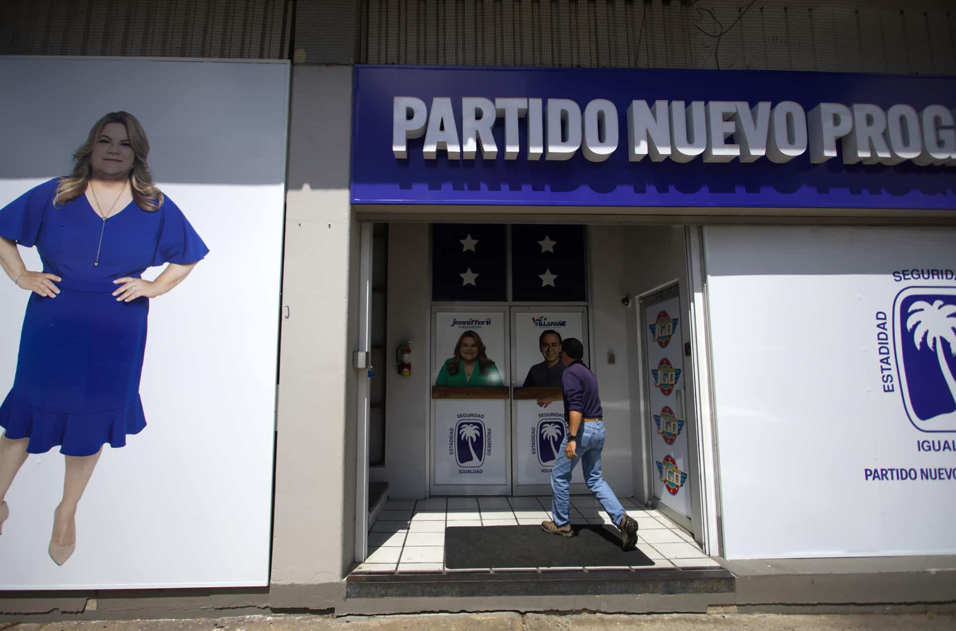 Fotografía del 25 de octubre de 2024 de un hombre entrando a la sede del Partido Nuevo Progresista (PNP), precedido por la foto de la candidata a gobernación, Jenniffer González, en San Juan (Puerto Rico). EFE/ Thais Llorca