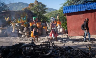 Personas pasan frente a los restos de una hoguera donde incineraron a un pandillero este martes, en una calle de Puerto Príncipe (Haití). EFE/ Johnson Sabin