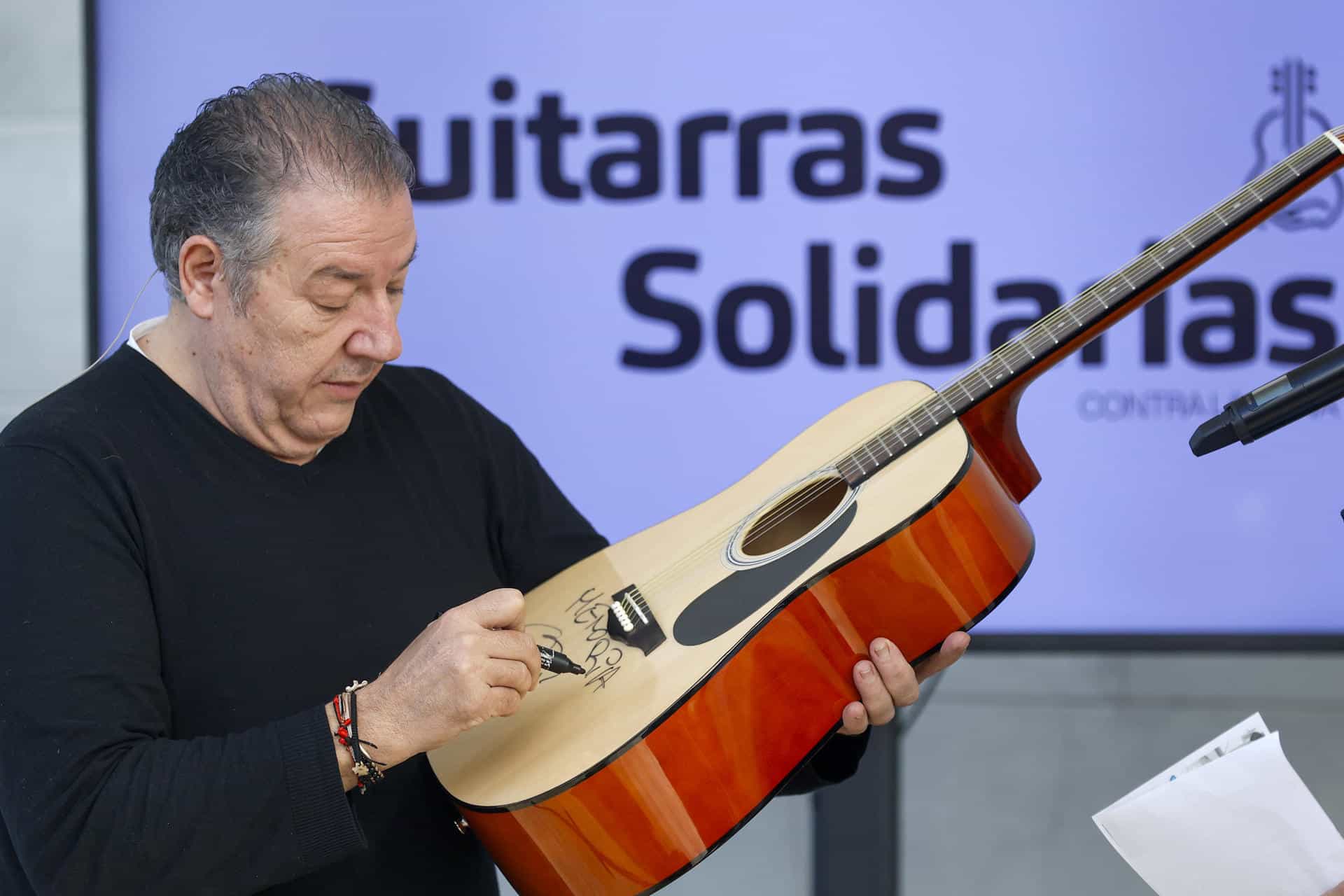 El músico español Carlos Goñi firma este lunes una de sus guitarras para que sea subastada a favor de los damnificados de las fuertes lluvias torrenciales de la provincia mediterránea de Valencia del 29 de octubre. EFE/ Miguel Ángel Polo