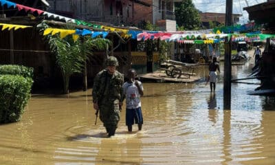 Fotografía cedida por el Ejército de Colombia que muestra a un solado acompañando a un joven por una calle inundada, en Alto Baudó (Colombia). EFE/Ejército de Colombia