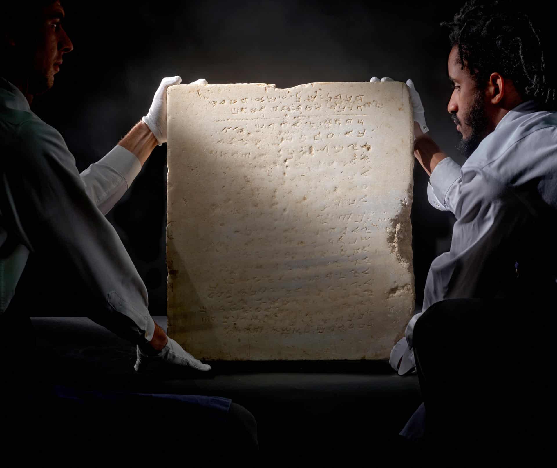 Fotografía cedida por Sotheby's donde aparecen dos de sus empleados mientras llevan una tableta de mármol de aproximadamente 1.500 años de antigüedad que contiene una versión en hebreo antiguo de los Diez Mandamientos bíblicos y que saldrá a la venta el próximo 18 de diciembre en una subasta organizada por esta casa de Nueva York. EFE/Sotheby's