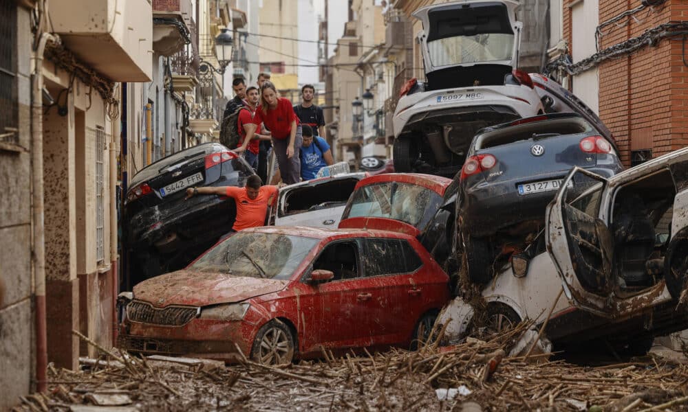 Vecinos de Paiporta intentan pasar entre una montonera de vehículos arrastrados por la corriente, este viernes. Las víctimas mortales en la provincia de Valencia a causa de la devastadora dana ha aumentado este viernes hasta las 205, según el último recuento facilitado por el Centro de Emergencias de la Generalitat Valenciana. EFE/Biel Aliño