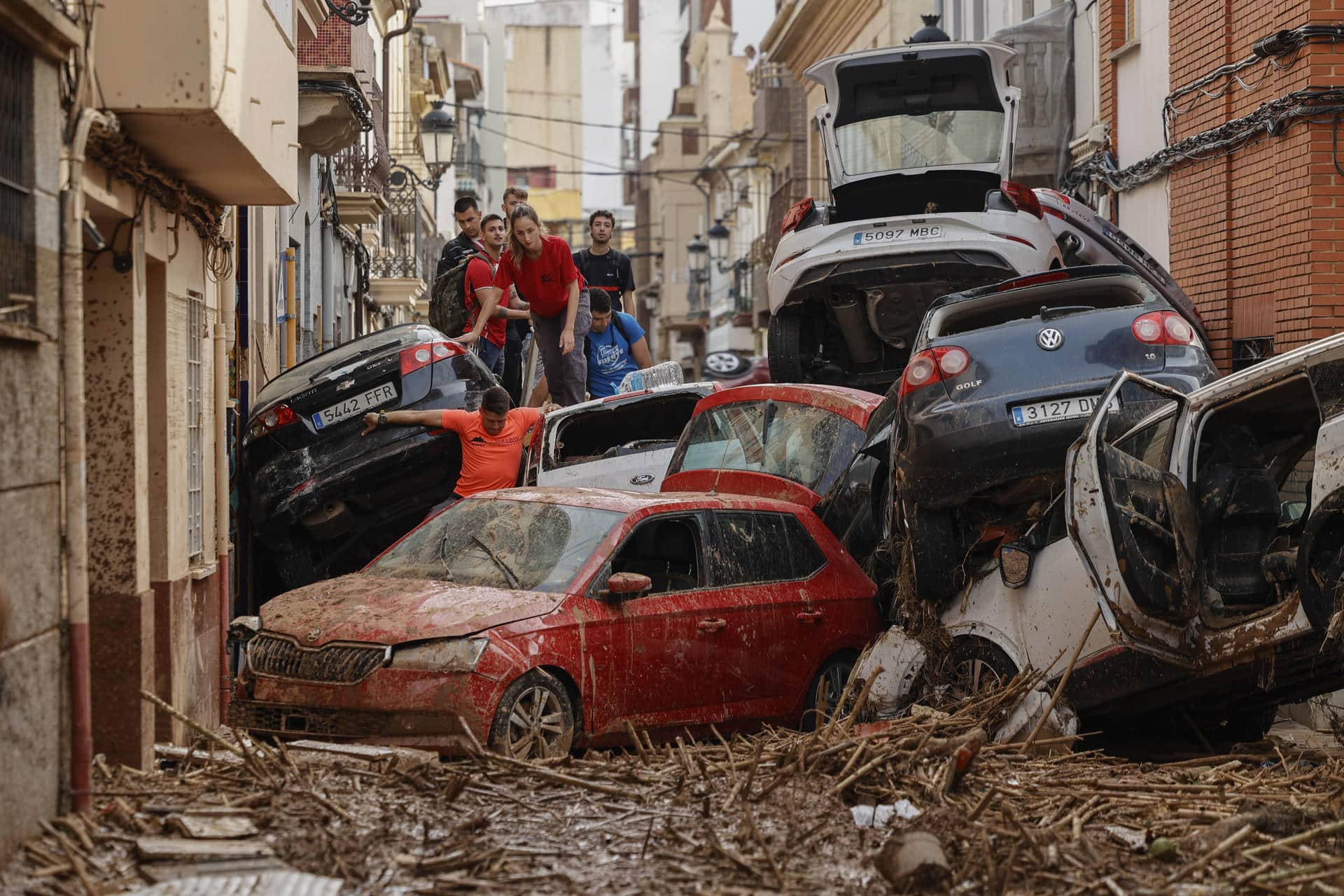 Vecinos de Paiporta intentan pasar entre una montonera de vehículos arrastrados por la corriente, este viernes. Las víctimas mortales en la provincia de Valencia a causa de la devastadora dana ha aumentado este viernes hasta las 205, según el último recuento facilitado por el Centro de Emergencias de la Generalitat Valenciana. EFE/Biel Aliño