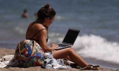 Una mujer toma el sol mientras mira su ordenador portátil. EFE/ Jorge Zapata/Archivo