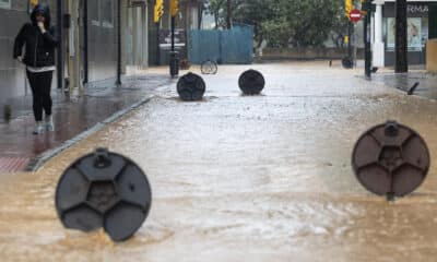 Una persona camina protegida para la lluvia por Gandía (Valencia) este miércoles. EFE/Natxo Francés