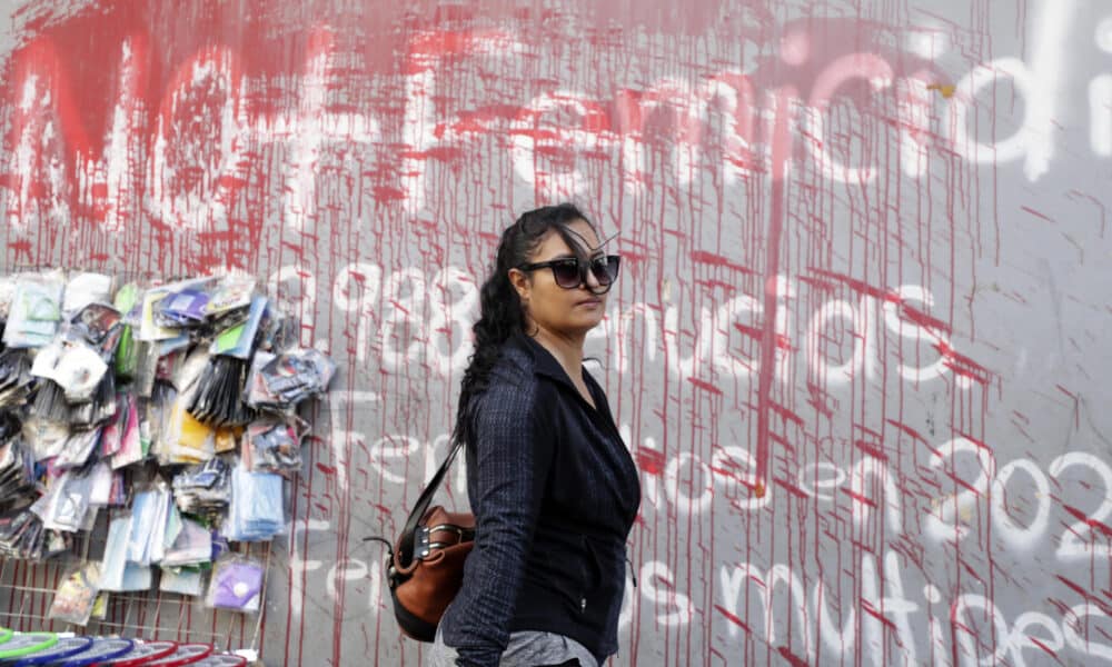 Fotografía de archivo en donde se ve a una mujer que camina frente a un muro pintado con un grafiti en contra de los feminicidios. EFE/STR