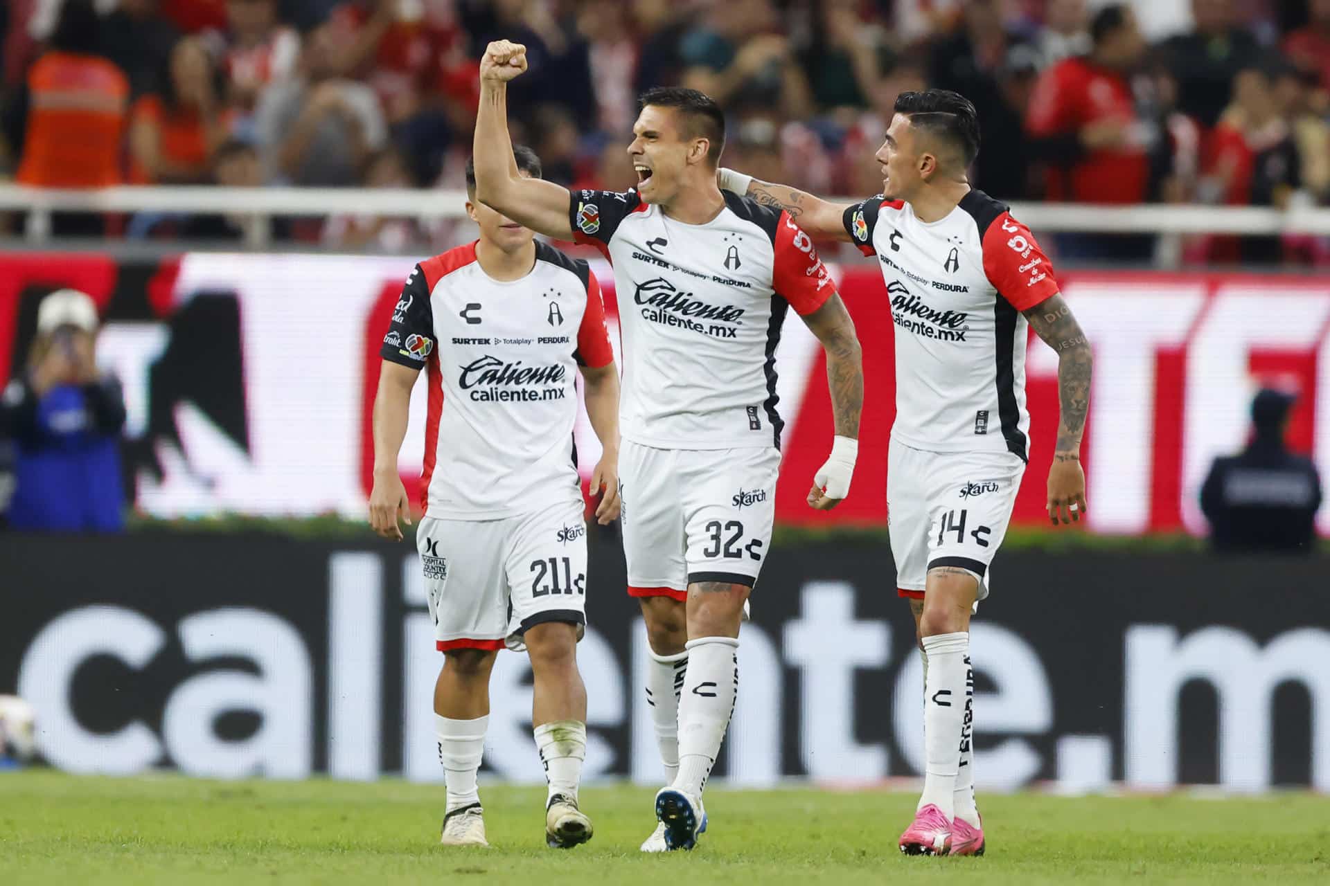 Uros Durdevic (c) junto a Luis Ricardo Reyes de Atlas celebran un gol este jueves, durante un partido de reclasificación del torneo apertura 2024 de la liga del fútbol mexicano entre Guadalajara y Atlas, en el Estadio Akron, en la ciudad de Guadalajara, Jalisco (México). EFE/ Francisco Guasco