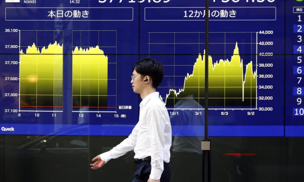 Fotografía de archivo de transeúnte que pasa por delante de un panel de indicadores bursátiles en Tokio (Japón). EFE/ Franck Robichon