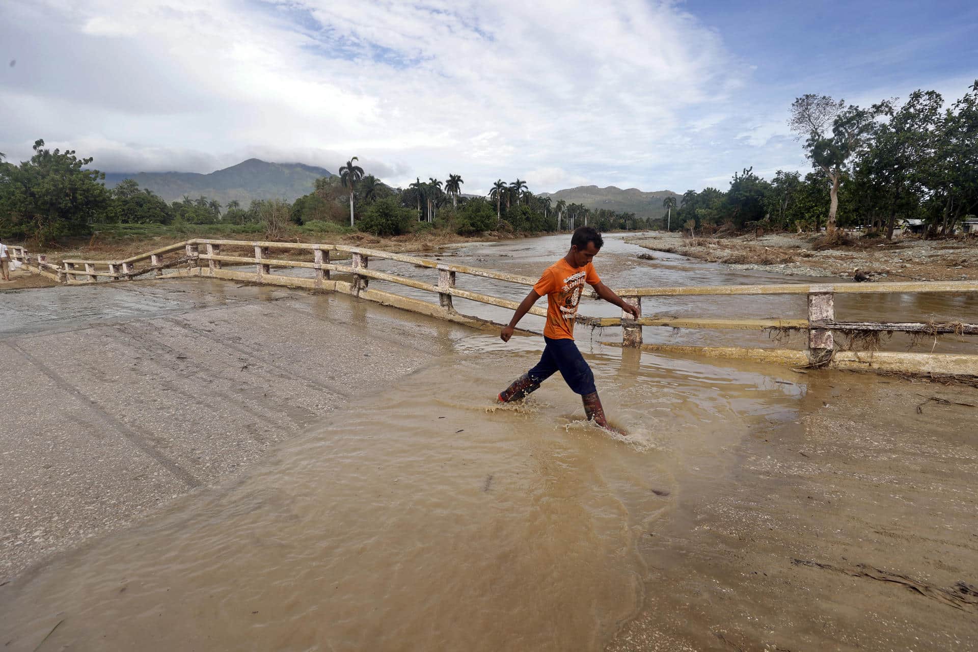 Fotografía de archivo del 29 de octubre de 2024 en donde un joven camina por una calle inundada en la región de San Antonio del Sur tras el paso de la tormenta tropical Óscar, en la provincia de Guantánamo, a más de 900 km de La Habana (Cuba). EFE/ Ernesto Mastrascusa