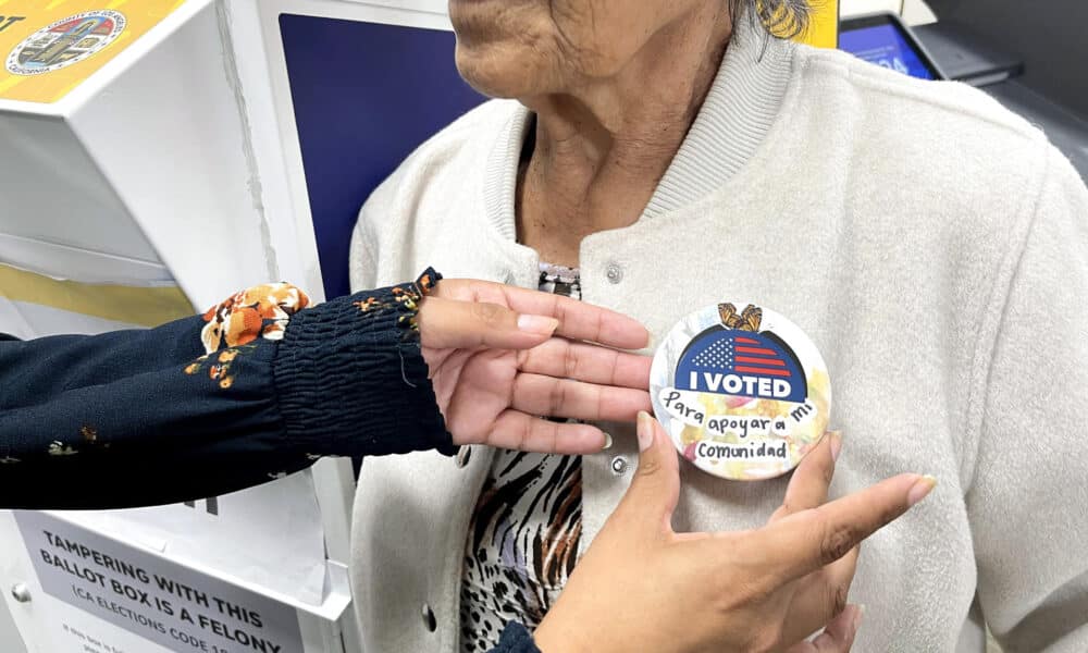 Fotografía del 2 de octubre de 2024 de una mujer recibiendo un botón después de votar en Los Ángeles, California (Estados Unidos). EFE/ Ana Milena Varón