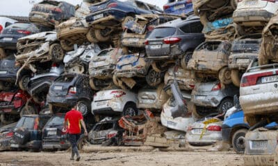 Un voluntario camina junto a una pila de vehículos destrozados en Paiporta, este martes. EFE/Jorge Zapata