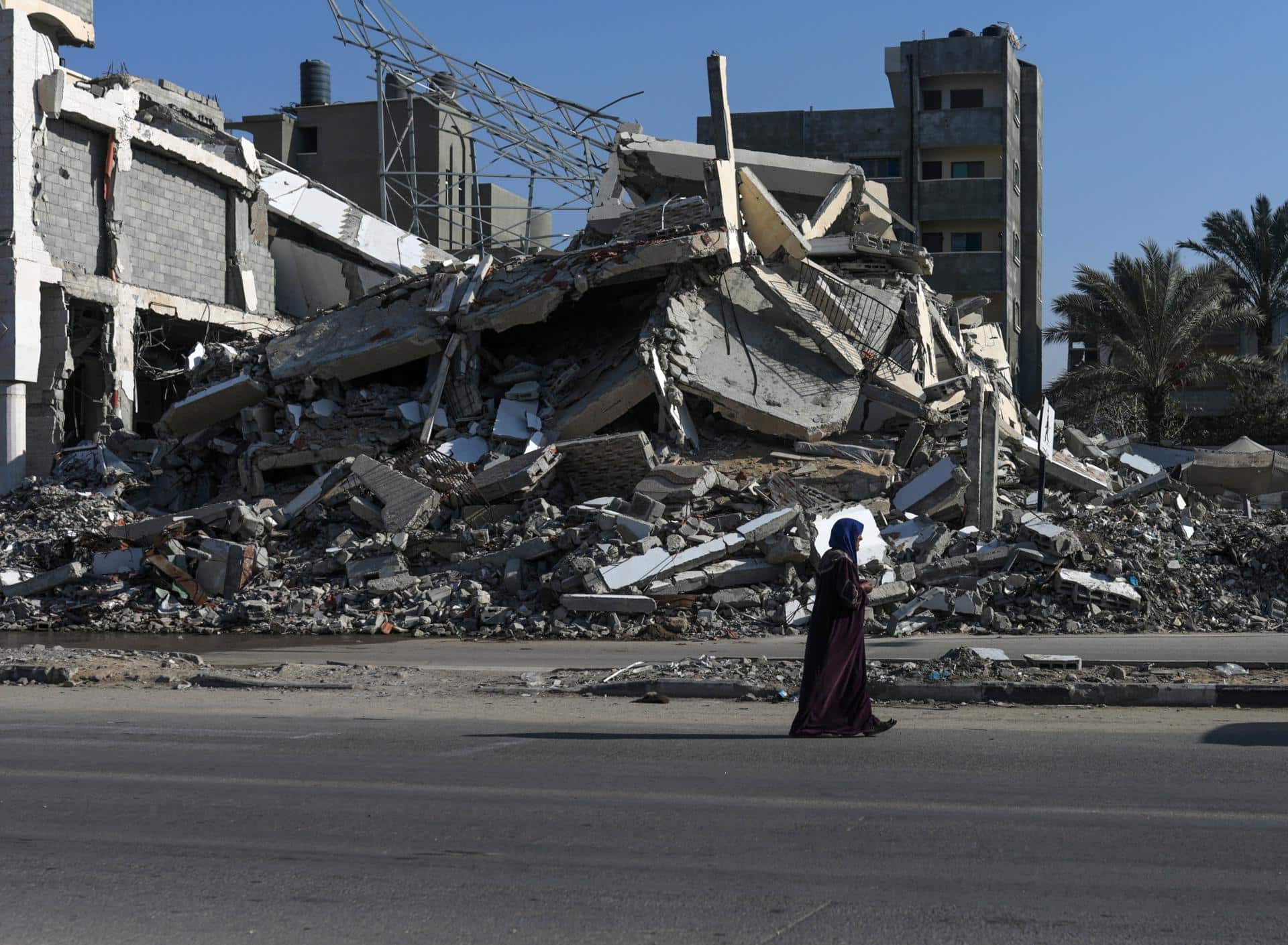 Una mujer pasa junto a casas destruidas en el campo de refugiados de Al Bureij, en el centro de la Franja de Gaza, el 21 de noviembre de 2024. EFE/EPA/MOHAMMED SABER