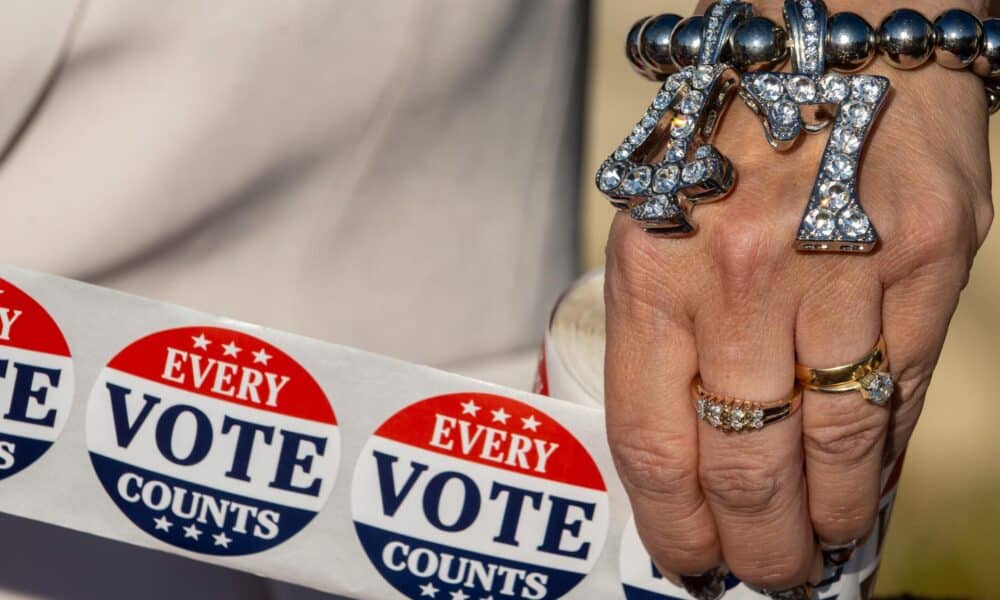 Un partidario de Trump que lleva una pulsera con la leyenda "47" sostiene pegatinas con la leyenda "Cada voto cuenta" fuera de un centro de votación el día de las elecciones en Filadelfia, Pensilvania, el 5 de noviembre de 2024.EFE/EPA/David Muse