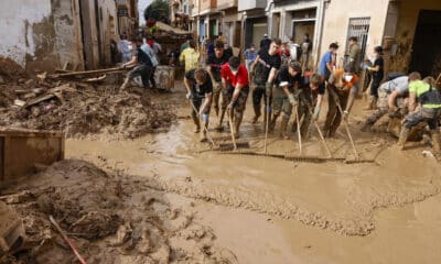 Voluntarios barren el lodo de una calle de Masanasa, Valencia, este jueves. EFE/Ana Escobar