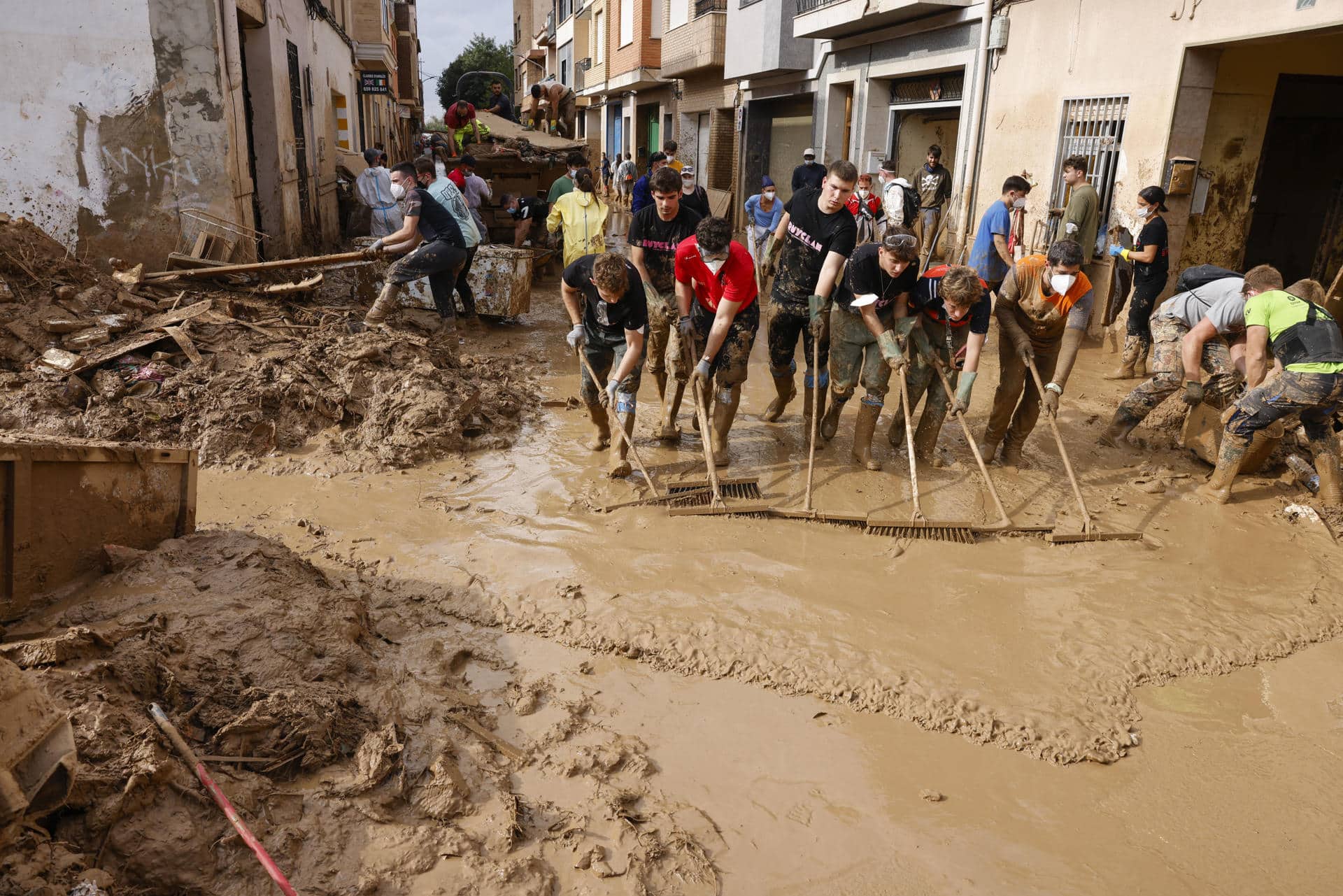 Voluntarios barren el lodo de una calle de Masanasa, Valencia, este jueves. EFE/Ana Escobar