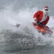 Un hombre disfrazado de Papá Noel hace figuras en una moto acuática antes de entregar regalos a niños con discapacidad este martes, en la playa de Copacabana en Río de Janeiro (Brasil). EFE/ Antonio Lacerda