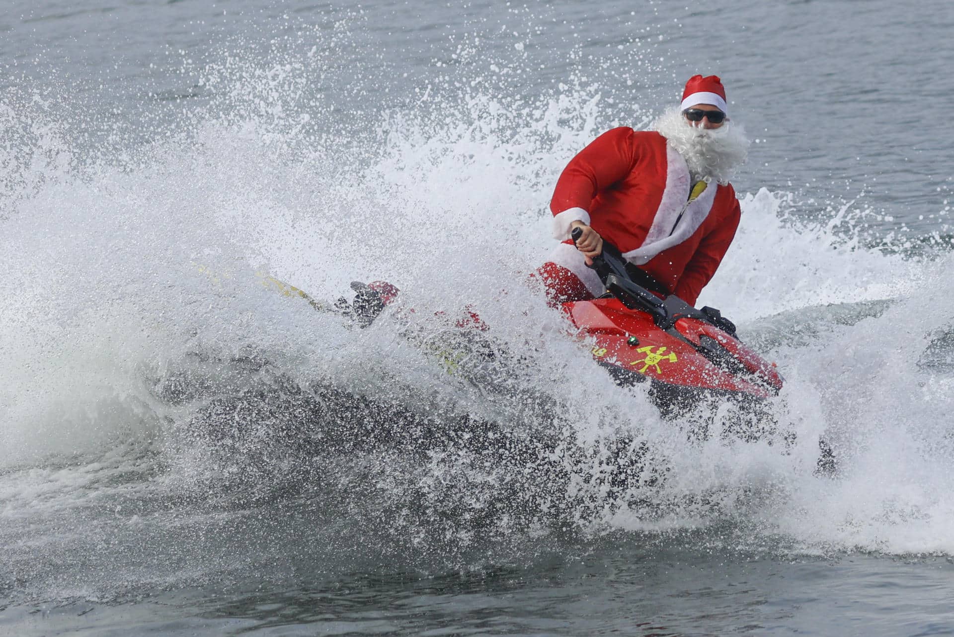 Un hombre disfrazado de Papá Noel hace figuras en una moto acuática antes de entregar regalos a niños con discapacidad este martes, en la playa de Copacabana en Río de Janeiro (Brasil). EFE/ Antonio Lacerda