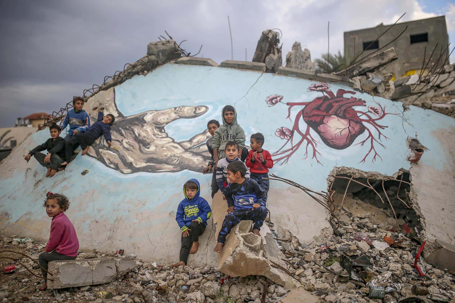 Foto de archivo de unos niños palestinos desplazados internamente juegan junto a un mural pintado sobre los escombros de una casa en Deir Al Balah, en la Franja de Gaza. EFE/ Mohammed Saber