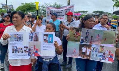 Familiares de los cuatro menores ecuatorianos desaparecidos sostienen carteles durante un plantón en los exteriores de la Fiscalía de Guayaquil este martes, en Guayaquil (Ecuador). EFE/ Cristina Bazán